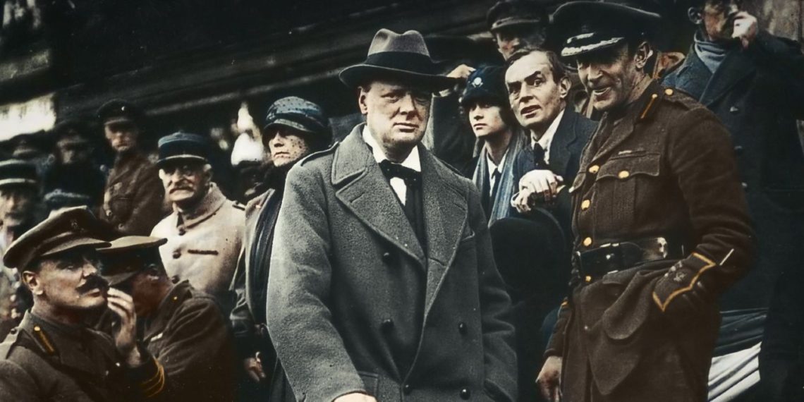 A younger Winston Churchill watching a march surrounded by uniformed officials in Churchill at War