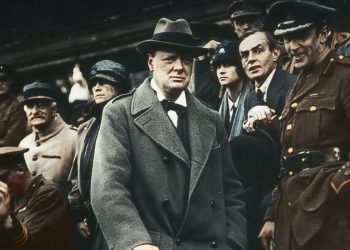 A younger Winston Churchill watching a march surrounded by uniformed officials in Churchill at War