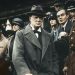 A younger Winston Churchill watching a march surrounded by uniformed officials in Churchill at War